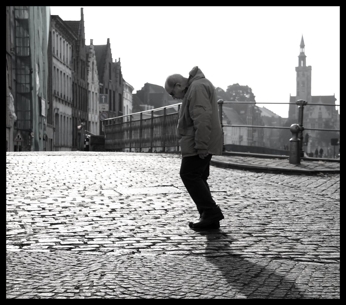 Very old man walking slowly through Bruges